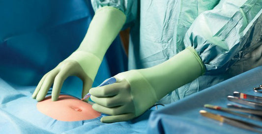 Surgeon wearing green nitrile surgical gloves performing a procedure in a UK operating theatre