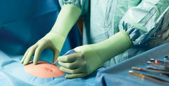 Surgeon wearing green nitrile surgical gloves performing a procedure in a UK operating theatre